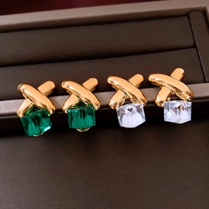 Detail of vintage square crystal earrings with emerald and clear stones in gold X-frame