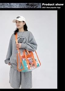 Detailed view of clear PVC tote bag featuring bright orange trim and cartoon print pouch