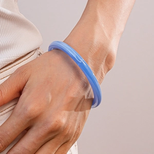 Gros plan d'un bracelet jonc en résine bleu ciel montrant une texture lisse et translucide