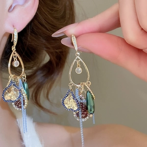 Detail of vintage gold earrings with heart pendants, colorful beads and crystal tassels