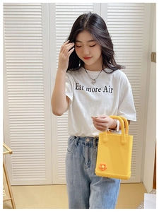 Gelbe EVA Strandtasche mit orangefarbener Blumendekoration gehalten von einem Model