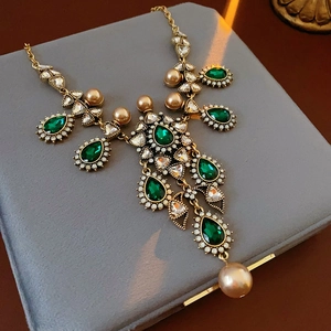 Detailed close-up of emerald teardrop gemstone and champagne pearls on a vintage necklace