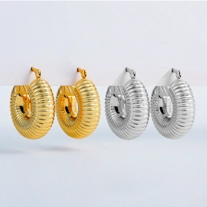 Detailed view of chunky hollow gold and silver hoop earrings with a textured spiral design