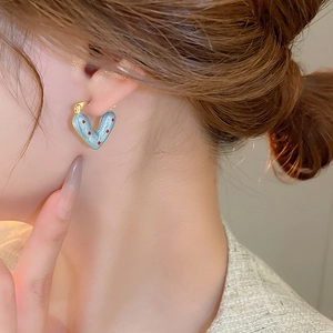 Close-up of light blue heart earrings with red dots on a model for daily wear