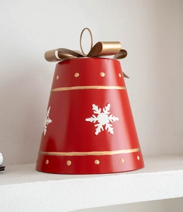 Close-up of red metal bell Christmas ornament with gold bow and white snowflakes