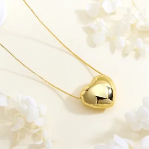 Detailed view of a 3D heart-shaped gold pendant necklace with a polished mirror finish