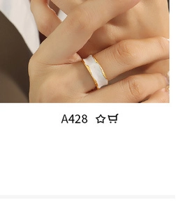 Detail of gold wavy ring with white marble inlay worn on model hand, minimalist jewelry
