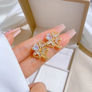 Macro shot of gold-plated clover stud earrings with sparkling zircon inlay details