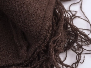 Close-up of dark brown knit scarf featuring detailed fringe tassels and soft yarn texture