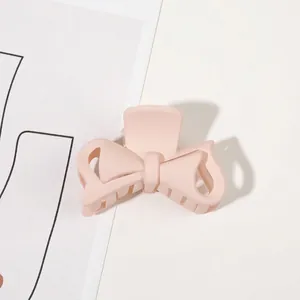 Detail view of the light pink matte bow hair claw clip showing a spring-loaded grip