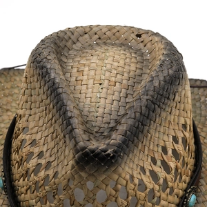 Detail of western straw cowboy hat featuring vintage turquoise buckle and leather band