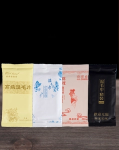 Four premium disposable wet towel packets in diverse elegant patterns on dark wood background