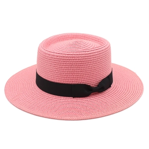 Macro detail of pink straw boater hat weave with a black grosgrain ribbon bow