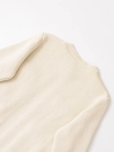 Dettaglio del girocollo e della trama a maglia fine di questo maglione in color crema