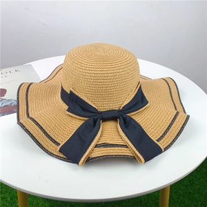 Detailed view of a wide-brimmed straw sun hat with a decorative black ribbon bow