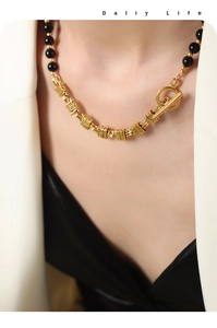 Detail of beaded necklace with black agate and gold OT toggle clasp worn by a model