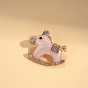 Close-up of pink enamel rocking horse brooch with white rhinestones on beige leather