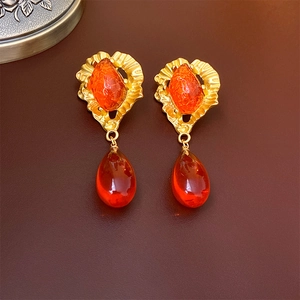 Detail of vintage gold earrings featuring orange gemstones in a teardrop design