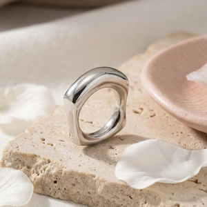 Artistic view of an irregular silver geometric ring on a textured stone base with petals