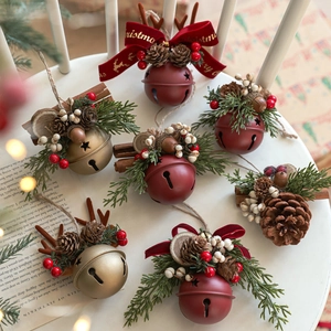 Christmas bell ornaments set with pine cones and berries on a white wooden chair