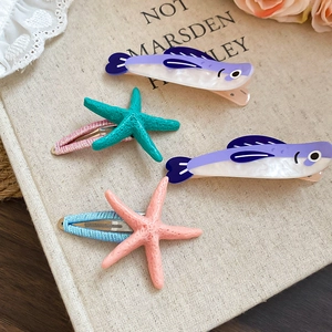 Detailed shot of acrylic fish and starfish hair clips set on a vintage book