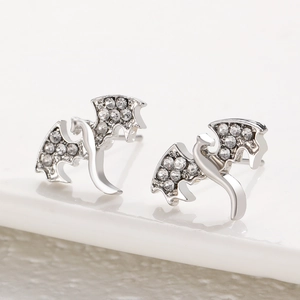 Vue macro des boucles d'oreilles dragon argentées avec strass blancs et ailes en métal