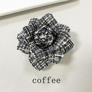 Detail of coffee brown tweed camellia brooch with a retro houndstooth pattern weave