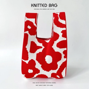 Detail of red and white floral knit tote bag showing thick texture and woven flower patterns