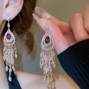 Macro shot of colorful beaded tassel earrings with a teardrop burgundy center stone