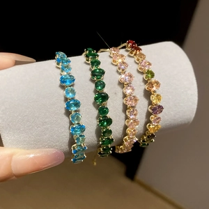 Gros plan de quatre bracelets dorés élégants sertis de zircons ovales colorés