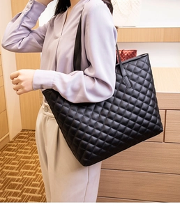 Model showing large black quilted faux leather tote bag with elegant diamond stitching
