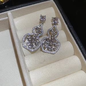 Macro shot of silver hollow gourd earrings with cubic zirconia and filigree details