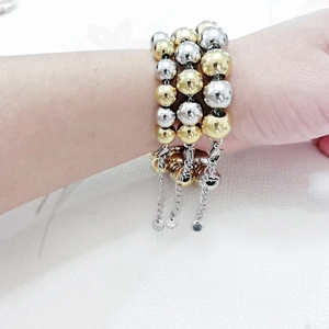 Detail of layered gold and silver stainless steel beaded bracelets with lobster clasps