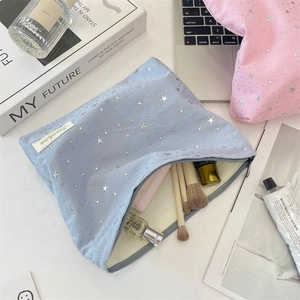 Detail of blue makeup bag with silver stars pattern and smooth zipper closure