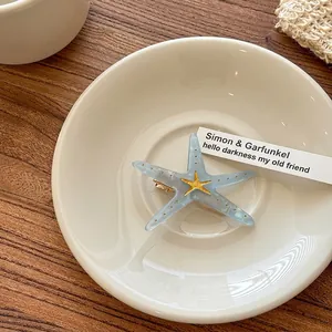 Detail view of acrylic starfish hair clip with blue marble texture on a white tray