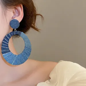 Oversized oval hoop earrings featuring denim fabric patchwork in three shades of blue