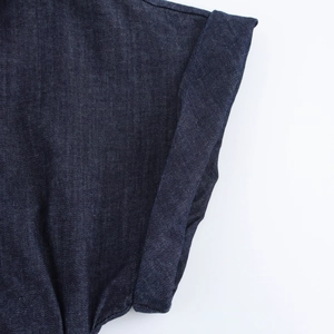 Dettaglio ravvicinato del polsino arrotolato di un abito in denim blu scuro con scollo a V