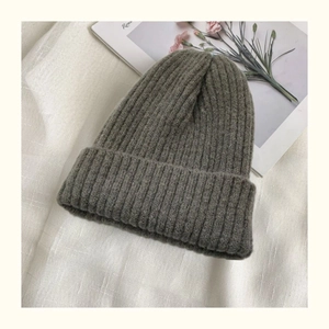 Macro shot of grey knitted winter hat texture and warm thick wool material on fabric