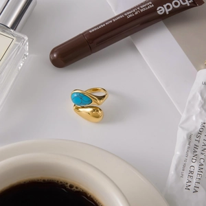 Detailed close-up of a gold titanium ring with a turquoise stone set on a neutral surface
