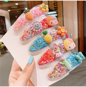Close-up of seven cartoon fruit and floral hair clips with sequins on a white card display