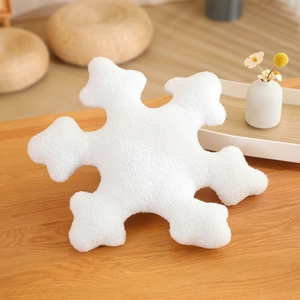 White snowflake shaped plush pillow made of soft lamb wool on a warm wooden surface