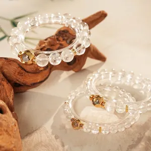 Elegant white crystal beaded bracelet set with gold heart charms on natural wood surface