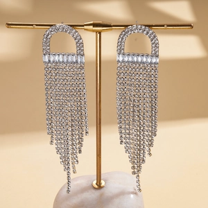 Detailed close-up of jellyfish tassel earrings with zircon stones on a golden display stand