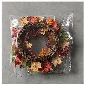 Overhead detail view of an autumn artificial maple leaf wreath in a clear plastic bag