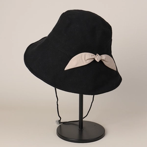 Detail of a black sun hat with a beige bow and adjustable windproof strap for women