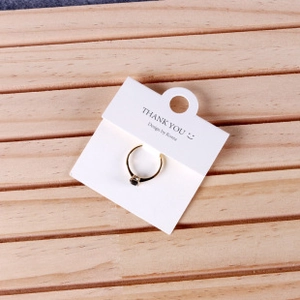 Detail of a gold ring with a black gemstone mounted on a white jewelry display card
