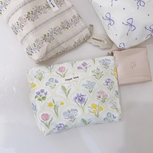 Détail de trois pochettes cosmétiques en tissu fleuri avec fermeture éclair