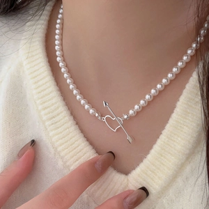 Close-up of pearl necklace with silver cupid heart buckle on a model's neck