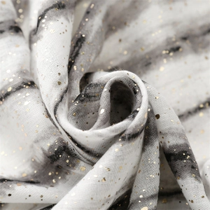 Detailed close-up of cotton linen scarf texture with gold foil and grey tie-dye pattern
