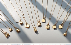 Close-up of assorted 18K gold plated titanium steel pendants on a soft grey background
